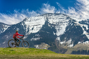 pretty mid age woman riding her electric mountain bike in early springtime in the Allgau mountains...
