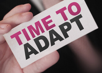 Time To Adapt on a card in businessman had. Business crisis management concept
