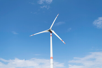 Wind turbine that stand out against the blue summer sky of the Tuscan countryside