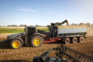 Tractor and combine harvester on a field during harvest