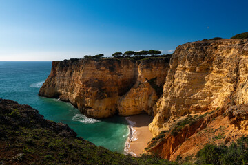 View of a small secluded beach surrounded by cliffs in Algarve, Portugal