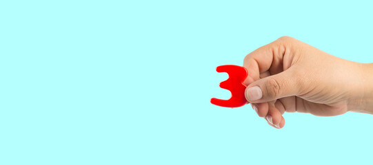 Woman's hand holding plastic number symbol, close up image