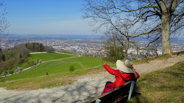 junge Frau auf Bank genie&szlig;t Aussicht vom Berg Achalm auf  Felder und Wald am Wanderweg im Fr&uuml;hling