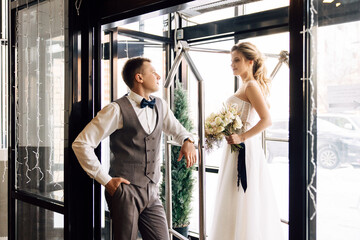 Caucasian happy young couple getting ready for wedding day at hotel. Girl bride laughs and stands...