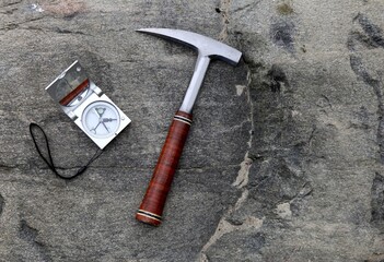 Geologists compass on the stones with hammer. Geology science concept. The geologist's hammer and tools are laid out on a stone