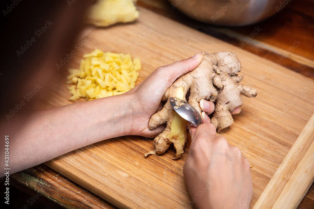 Wall mural peeling or peel off ginger with a spoon, preparation in the kitchen