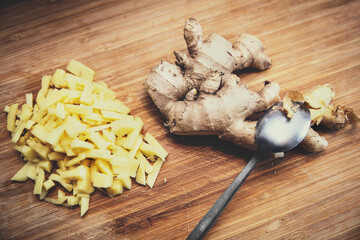 Ginger peeled with a spoon, chopped bites beside, wooden ground