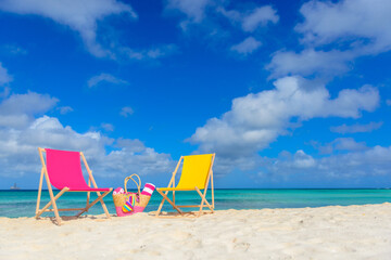 Colorful beach lounge chairs and beach bag at the beach