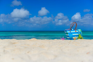 Fototapeta na wymiar Colorful beach bag with sunglasses, towel, bikini and flip flops at the beach