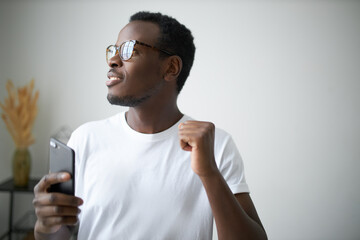 Joy, fun, leisure and electronic gadgets. Unshaven young black male in glasses having happy facial...