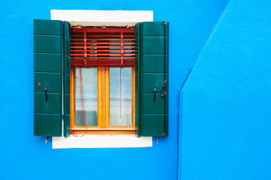 Window on the blue facade of the house. Colorful architecture in Burano island, Venice, Italy.