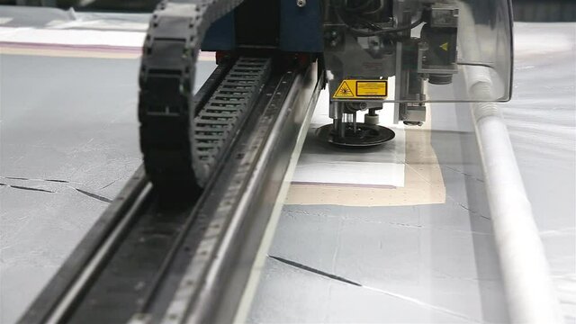 In an industrial garment factory, a special Laser Cutting Fabric cuts out certain textile pieces. Concept of: Laser machine, Work in a factory, Automatic cutting.