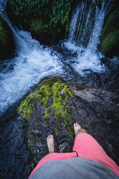 Hombre parado con los pies en el agua con cascadas en el bosque de la Patagonia Argentina Villa la angostura