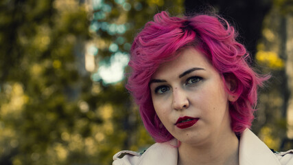 Chica joven de pelo rosa, Chica con ojos claros y labios rojos, chica pin up en el parque, mirando...