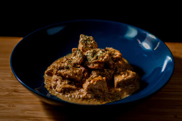 Chicken butter masala curry in a blue bowl garnished with green chopped leaves