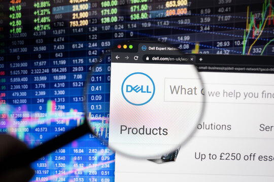 Dell company logo on a website with blurry stock market developments in the background, seen on a computer screen through a magnifying glass