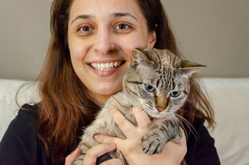 woman holding a tabby cat looking at camera