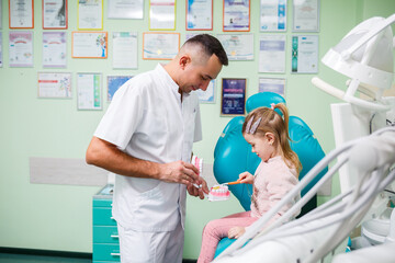 Professional doctor, pediatric dentist teaches a child to brush his teeth. Dental office for patient examination. The process of dental treatment in a child.