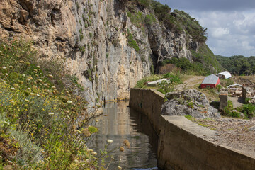 Ancient canal dug into the rock by the Etruscans. Ancient canal with murky water in the middle of the vegetation. Tagliata Etrusca, Ansedonia, Italy.