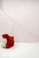 Red armchair in empty room against concrete stairs