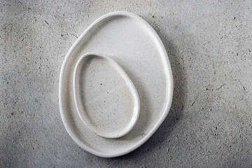 Two beige handmade ceramic avocado shaped plates on a grey concrete background. Copy space. Minimal...
