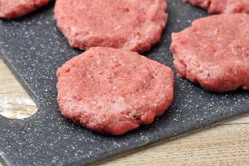 round raw beef cutlets on a board