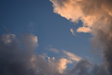 Dark rain clouds on a background of dark blue sky, illuminated by the sun to orange. Atmospheric phenomena