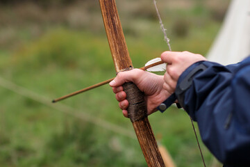 Closeup of hands preparing an arrow on the bow.
Archer is about to shoot the arrow with an ancient...