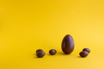 Easter chocolate eggs on yellow colored background. Creative still life, flat lay, pop art style