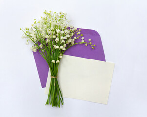 White flowers Lily of the valley ( Convallaria, May bells, may lily ), postal envelope with paper card note with space for text on a light background. Top view, flat lay. Spring decoration