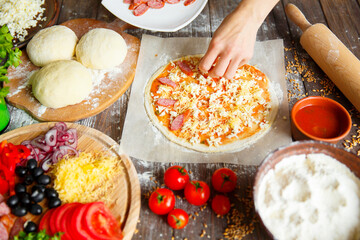 Cook in the kitchen putting the ingredients on the pizza. Pizza concept. Production and delivery of food