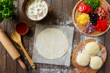 Pizza dough with ingredients on wood table