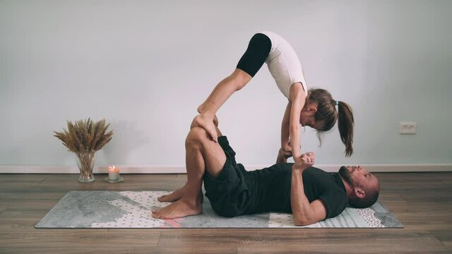 Caucasian man and girl do yoga online Dad lifts daughter on hands and feet Yoga for Beginners Happy Family Gymnastics Classes Funny Yoga