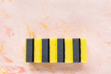 Set of new yellow and gray sponges for dishwashing on pink background. Domestic household and cleaning concept. Close up, copy space