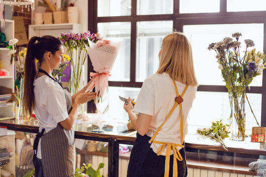 Women florists collect bouquets of flowers at their desk in a flower shop.