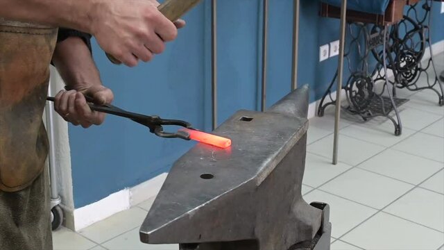 A blacksmith at work with glowing irons. Hot iron forge, a blacksmith at work with red-hot iron