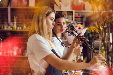 Women florists collect bouquets of flowers at their desk in a flower shop.