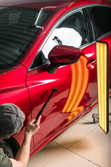 The technician removes dents on the car using the method without painting. PDR. Car body repair. - 431058253