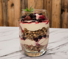 Nutrition and sweet desserts. Closeup view of a multilayer trifle with berries, oatmeal, granola,...