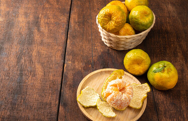 Orange ponkan, orange ponkan in a basket on rustic wooden light background, selective focus.