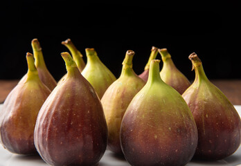 Purple figs, purple figs on a white plate on rustic wood, black background, selective focus.
