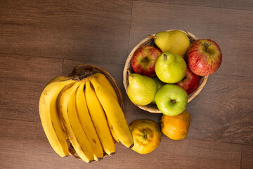 tropical fruit basket in detail on wooden surface, black background, selective focus.