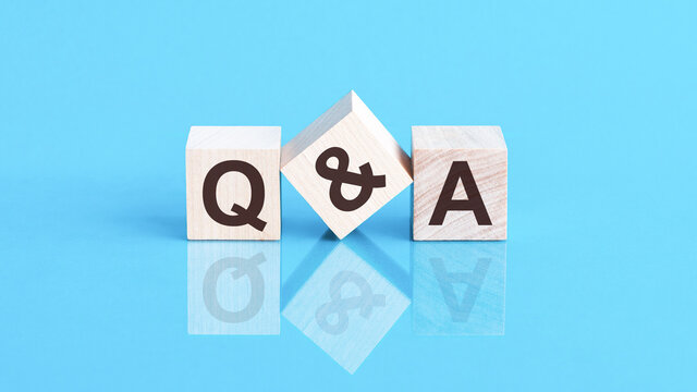 q and a word is made of wooden building blocks lying on the blue table, concept