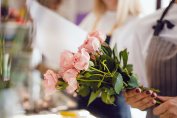 Young woman florist collects a bouquet of fresh roses.