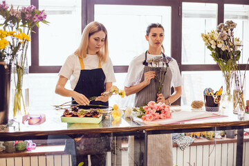 Florist girls collect bouquets of flowers at their desk in a flower shop.