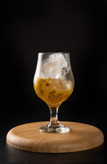 Brazilian Drink, Sake caipirinha with passion fruit in a bowl, on dark round wooden surface, black background, selective focus.