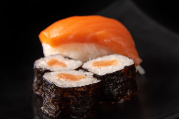 Sushi, beautiful arrangement of sushi made on black plate on dark surface, black background, selective focus.