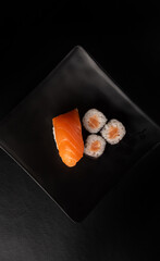 Sushi, beautiful arrangement of sushi made on black plate on dark surface, black background, top view.