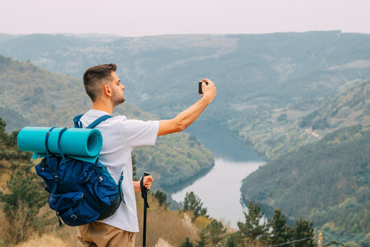young man hiking or hiking taking pictures with mobile phone