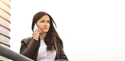 Beautiful brunette businesswoman talking on a cell phone in her hands on a light background with free copy space. Business concept